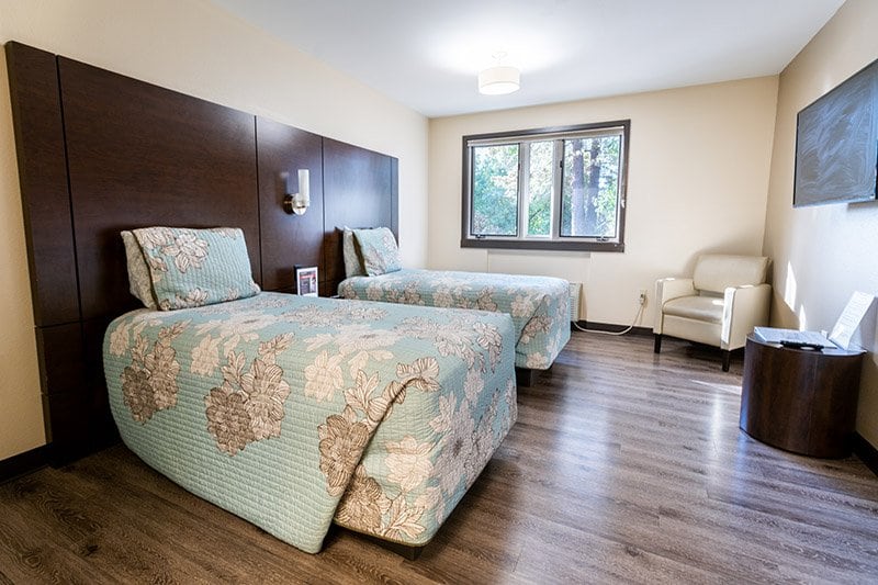 Guest room with twin beds, chair and window at the Francis Cheney Family Place