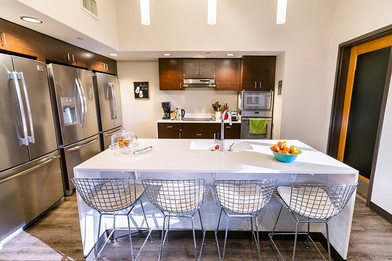 Communal kitchen with island, chairs refrigerators and meal preparation area