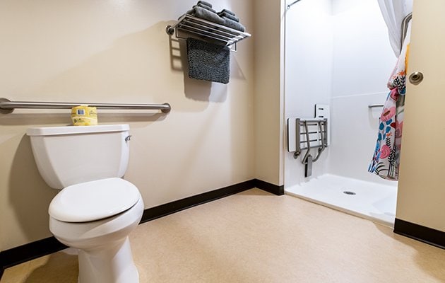 ADA accessible bathroom with toilet, shower and towel rack